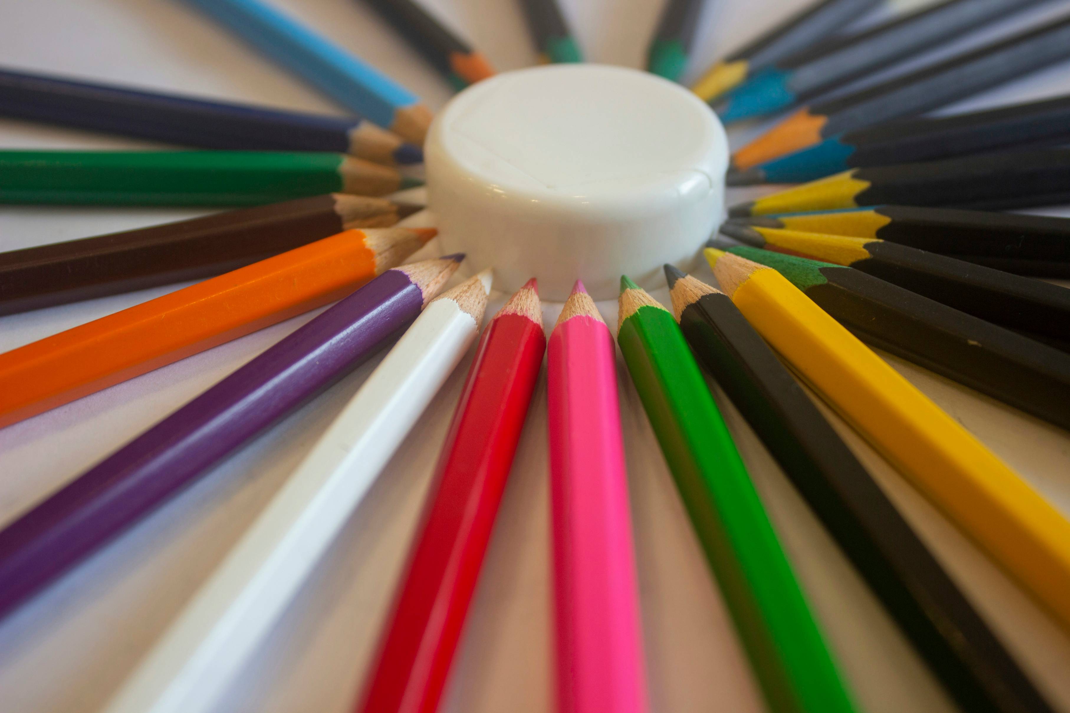 white round plastic container on multicolored color pencils