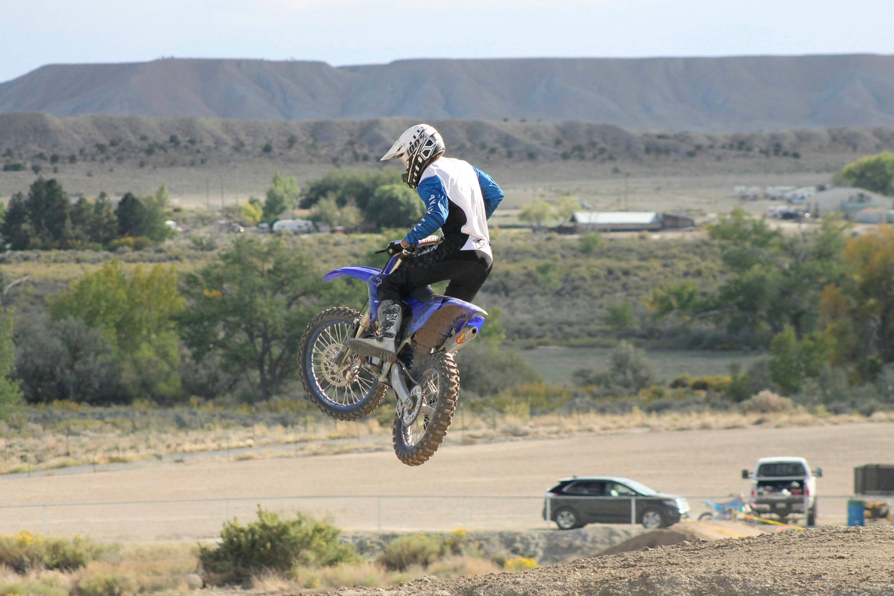 Motorcyclist jumps over dirt track in arid landscape