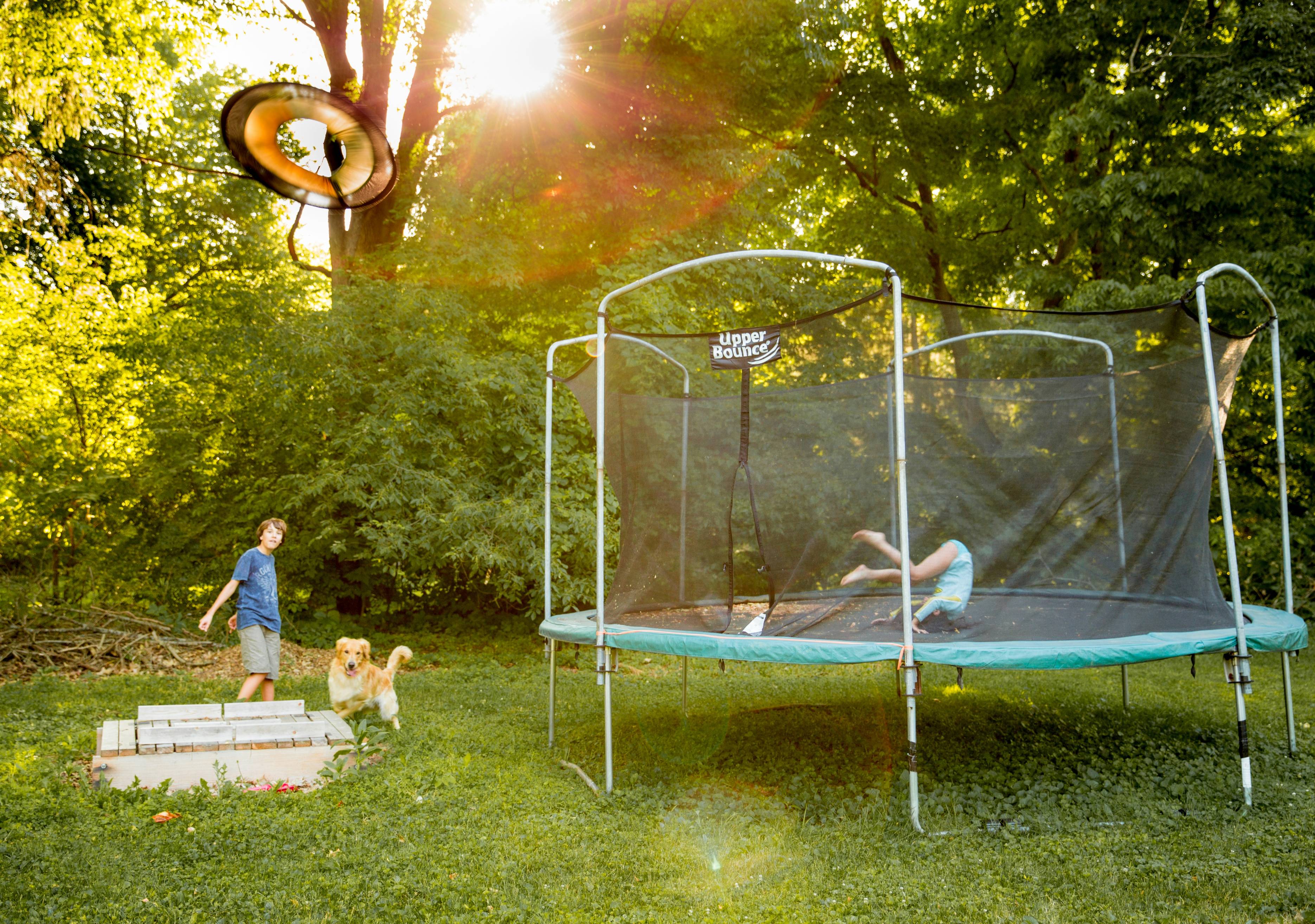 two children playing on a trampoline in a yard